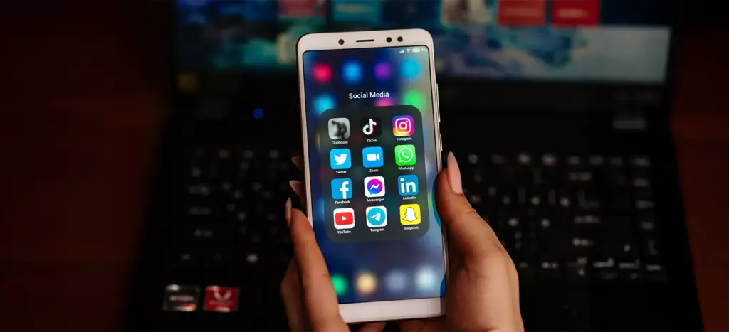 Person holding smartphone showing social media apps, representing mobile apps for business growth.